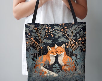 May include: A black tote bag with a design of two foxes cuddling in a forest setting. The foxes are orange and white, and the forest is filled with green leaves and branches. The background is a dark blue with white stars.