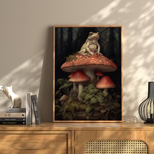 May include: A white frog sits on top of a large red and white mushroom in a forest setting. The mushroom is surrounded by smaller mushrooms and green foliage.