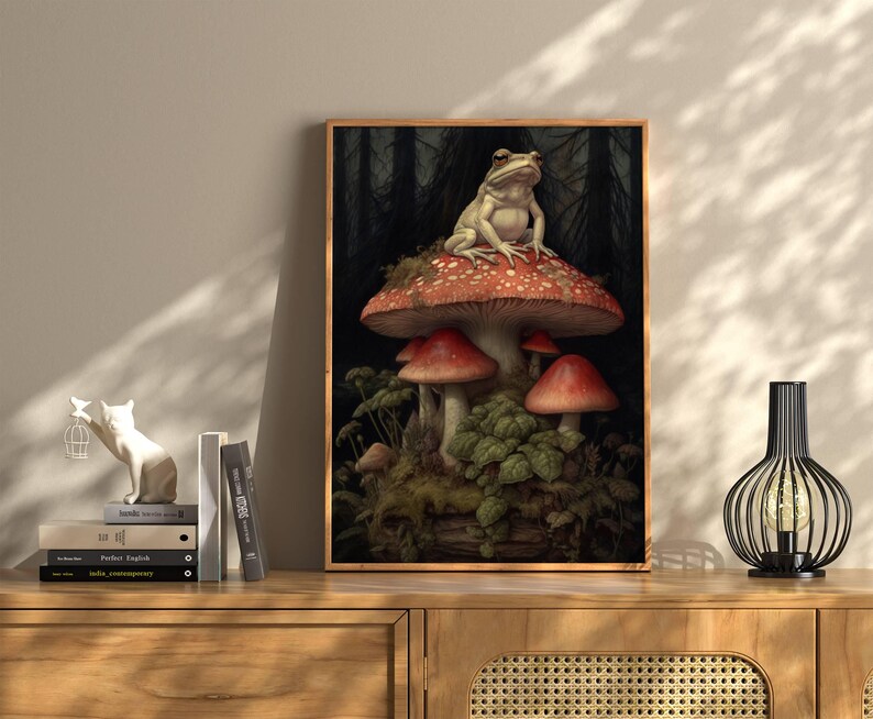 May include: A white frog sits on top of a large red and white mushroom in a forest setting. The mushroom is surrounded by smaller mushrooms and green foliage.