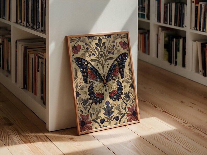 Puede incluir: Una impresi&oacute;n art&iacute;stica enmarcada con una ilustraci&oacute;n detallada de una mariposa. La mariposa tiene marcas azules, rojas y amarillas sobre un fondo floral beige. La obra de arte est&aacute; en un marco de madera, apoyada contra una pared blanca cerca de una estanter&iacute;a.
