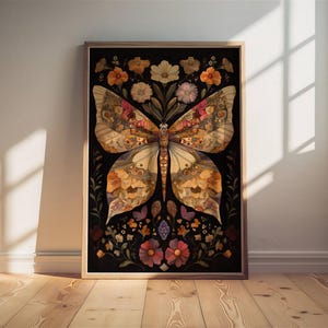 May include: A framed print of a butterfly made from pressed flowers and leaves. The butterfly is a light brown color with dark brown and black accents. The background is black and features a variety of flowers in shades of pink, purple, and yellow.