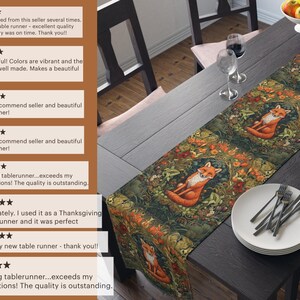 May include: A table runner with a forest scene featuring foxes, flowers, and leaves. The runner is green, brown, and orange. The runner is on a wooden table with a plate and silverware.