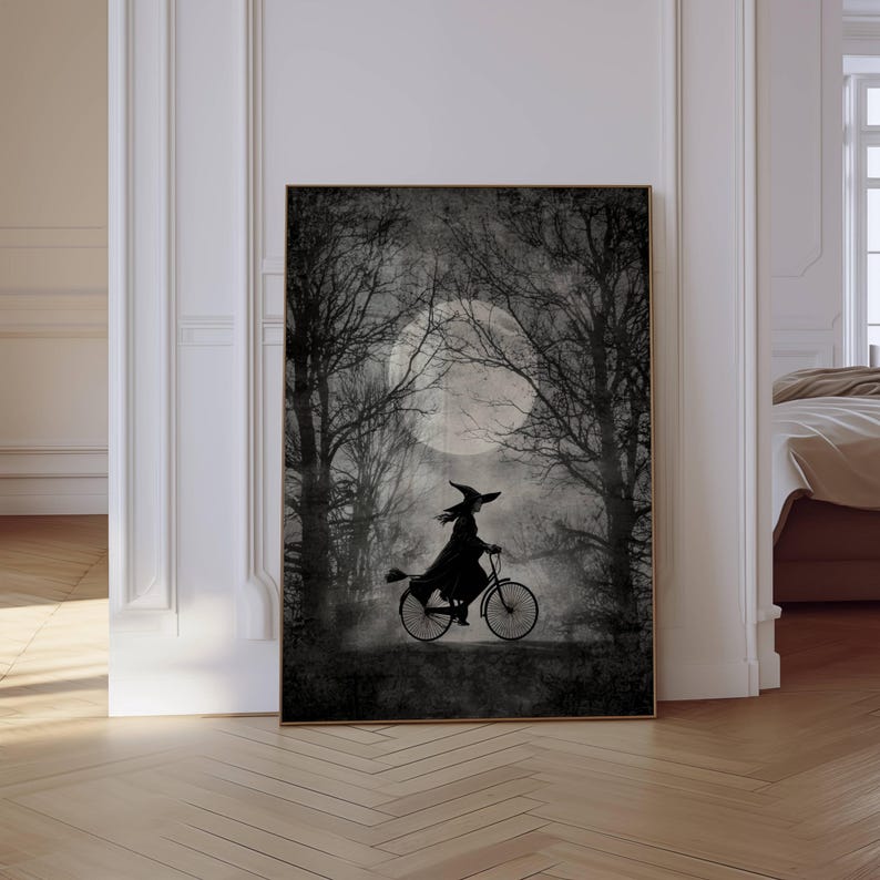 K&ouml;nnte beinhalten: Schwarz-wei&szlig; gerahmter Kunstdruck mit einer Hexe auf einem Fahrrad in einem Wald unter einem Vollmond. Das Bild hat ein Vintage-Thema mit silhouetten B&auml;umen und einer nebligen Atmosph&auml;re, passend f&uuml;r Halloween.