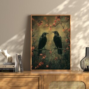 May include: A framed print of two black crows perched on branches in a forest setting. The crows are facing each other and appear to be communicating. The background is a soft, muted green with pink blossoms.