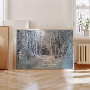 Puede incluir: Una impresi&oacute;n art&iacute;stica enmarcada que representa un paisaje de bosque nevado. El camino serpentea a trav&eacute;s de un bosque de abedules, con sus troncos blancos destacando sobre la nieve. La impresi&oacute;n est&aacute; en un marco de madera clara.