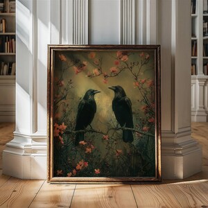 May include: A framed print of two black crows perched on branches in a forest setting. The crows are facing each other and the background is a soft green and brown with pink flowers.