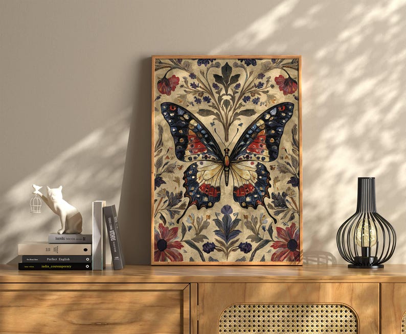 Puede incluir: Una impresi&oacute;n art&iacute;stica enmarcada de una mariposa. La mariposa tiene intrincados patrones en las alas en tonos de azul, rojo y amarillo. El fondo presenta motivos florales y de hojas en tonos apagados. La obra de arte se exhibe en un mueble de madera.