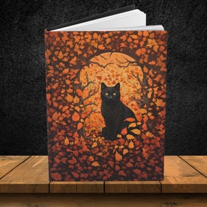 May include: A black cat with yellow eyes sits in a circle of orange and brown leaves. The cat is looking directly at the viewer. The background is a dark orange and brown.