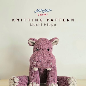 Puede incluir: Un juguete Mochi Hippo tejido en tonos morados y beige. El hipopótamo tiene dientes grandes y blancos y está sentado con las patas extendidas. La imagen también incluye el texto "Moy Moy Knits" y "Knitting Pattern Mochi Hippo."