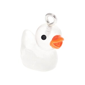 May include: A clear, translucent duck-shaped charm featuring a bright orange beak and a small black eye. A silver-toned metal jump ring is attached to the top of the duck's head, allowing it to be easily suspended from a necklace or bracelet chain.