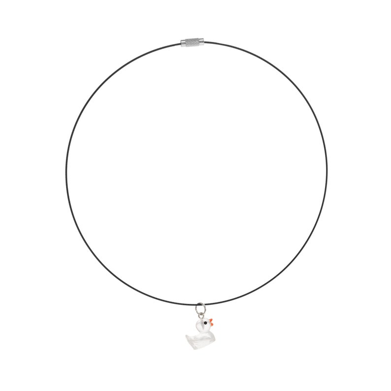 May include: A black cord necklace featuring a small, clear glass duck pendant with a bright orange beak and a tiny black eye. The necklace is secured with a silver-toned cylindrical metal clasp at the top, completing the circular design.