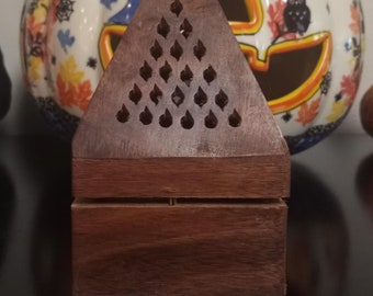 May include: A wooden triangular incense burner with a decorative pattern of small holes. The burner is made of dark brown wood and has a two-tiered design.