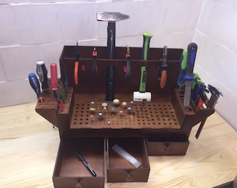 May include: A wooden tool organizer with a variety of tools, including screwdrivers, pliers, a hammer, and a sanding block. The organizer has a pegboard with holes for storing tools, as well as two drawers for additional storage.