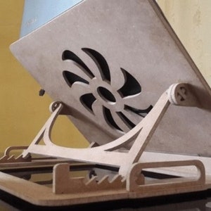 May include: A wooden laptop stand with a cutout design in the shape of a fan. The stand is made of light brown wood and has a raised platform for the laptop to sit on. The stand is designed to help cool the laptop and improve ergonomics.