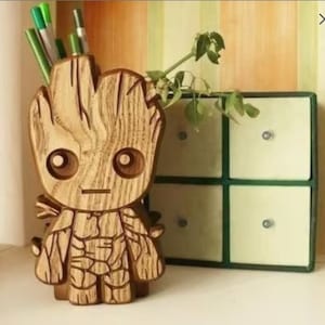 Può includere: Portapenne in legno a forma del personaggio Groot del film Guardiani della Galassia. Il portapenne è marrone e presenta una scultura dettagliata del viso e del corpo di Groot.