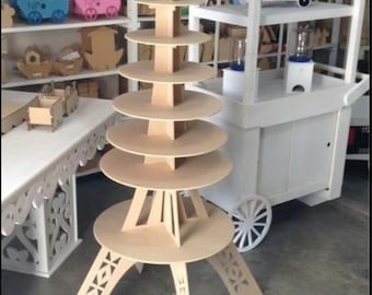 May include: A wooden Eiffel Tower-shaped cake stand with six tiers. The stand is made of unfinished wood and has a decorative design on the base.