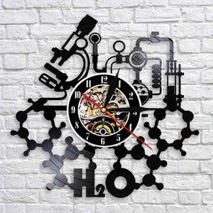 May include: Black and white vinyl record clock with a science theme. The clock features a microscope, a beaker, and a chemical formula for water, H2O. The clock face is a steampunk-style design with gears and cogs.