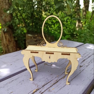Puede incluir: Un tocador de madera con un espejo redondo y una mesa con tres cajones. El tocador está hecho de madera clara y tiene un diseño delicado.