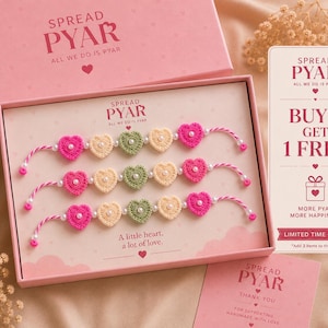 Puede incluir: Una caja de regalo rosa con tres pulseras de corazón de ganchillo. Cada pulsera tiene corazones rosas, crema y verdes con detalles de perlas. La caja y la tarjeta muestran el texto "SPREAD PYAR" y "A little heart, a lot of love."