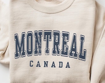May include: A beige sweatshirt with a navy blue vintage-style graphic that reads "MONTREAL CANADA".