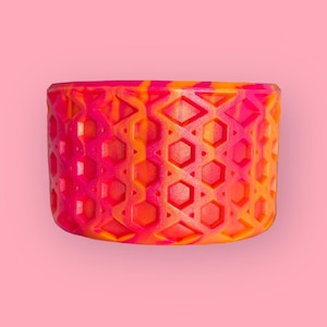 May include: A bright orange and pink patterned roller skate wheel with a honeycomb design.