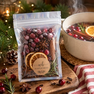 May include: A clear, resealable pouch filled with dried cranberries, star anise, cinnamon sticks, orange slices, and rosemary sprigs. A round, tan paper label on the front features the text "wb DIY WILD BOTANICALS" with a small botanical illustration.