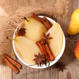 K&ouml;nnte beinhalten: Eine wei&szlig;e Sch&uuml;ssel gef&uuml;llt mit pochierten Birnen, Zimtstangen und Sternanis. Die Birnen sind durchscheinend und haben eine hellgelbe Farbe. Die Sch&uuml;ssel steht auf einer Holzoberfl&auml;che mit einem Jutesack im Hintergrund.