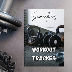 May include: A black and white workout tracker notebook with a spiral binding. The cover features a photo of weights and kettlebells with the text "Samantha's Workout Tracker".