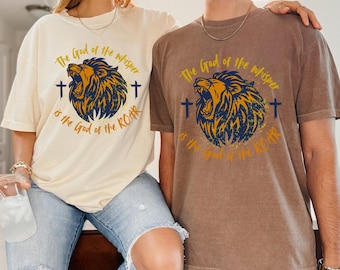 May include: Two short-sleeved t-shirts, one cream and one brown, featuring a lion graphic with the text "The God of the whisper is the God of the ROAR". The lion is yellow and blue.