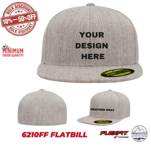 Puede incluir: Una gorra de visera plana en color gris jaspeado con corona estructurada. El panel frontal muestra el texto negro YOUR DESIGN HERE. La gorra incluye una pegatina circular en la visera y está etiquetada como modelo 6210FF de Flexfit.