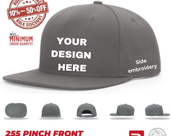 May include: A charcoal grey structured snapback cap with a flat brim. The front panel features the white text YOUR DESIGN HERE. The side of the cap includes the white text Side embroidery. Five smaller views of the cap are shown below the main image.
