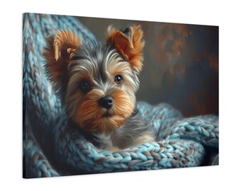 May include: A canvas print of a Yorkshire Terrier puppy nestled in a blue knitted blanket. The puppy has brown and black fur with tan ears and a focused gaze. The background has muted orange and blue tones.
