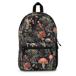 Può includere: Zaino nero con un motivo botanico con funghi, bacche e fogliame nei toni del rosso, beige e verde. Lo zaino ha un manico nero, una cerniera e una tasca laterale in rete. Il design è un motivo ripetitivo di piante stilizzate.