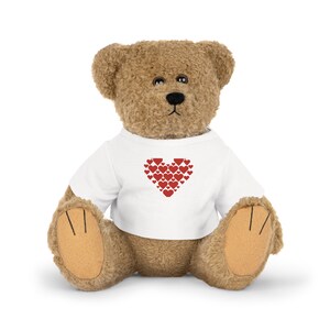 Könnte beinhalten: Ein brauner Teddybär, der ein weißes T-Shirt mit einem roten Herz aus kleineren Herzen auf der Vorderseite trägt.