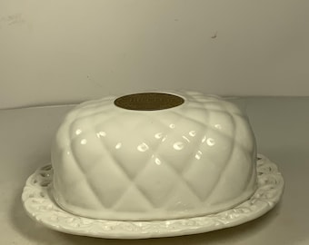 May include: White ceramic butter dish with a quilted design and a decorative lid. The lid has a raised, circular design with the word "Butter" embossed on it.