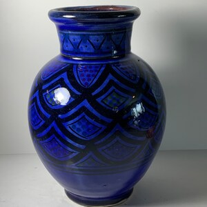 May include: A blue ceramic vase with a geometric pattern. The vase has a round body and a narrow neck.