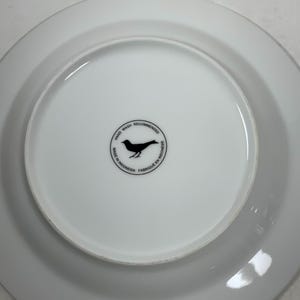 May include: White ceramic plate with a black bird logo that reads "Hand Wash Recommended, Made in Indonesia, Fabriqu&eacute; en Indon&eacute;sie".