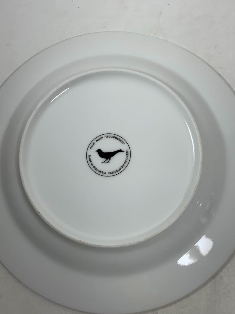 May include: White ceramic plate with a black bird logo that reads "Hand Wash Recommended, Made in Indonesia, Fabriqu&eacute; en Indon&eacute;sie".