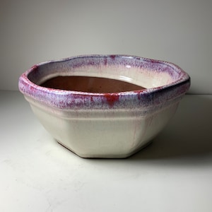 Könnte beinhalten: Ein weißer Keramiktopf mit einem violetten und roten Überzug. Der Topf hat eine achteckige Form und eine breite, flache Schale.