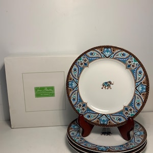 Puede incluir: Juego de platos decorativos Vera Bradley. Los platos tienen un centro blanco con un pequeño diseño de elefante y un borde de patrones de cachemira azules, turquesas y marrones. Se ve una caja blanca con el logotipo de Vera Bradley.