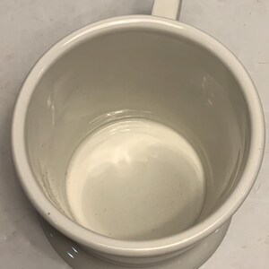 Puede incluir: Una taza de cer&aacute;mica blanca con asa. La taza tiene una forma cil&iacute;ndrica ancha con un borde ligeramente ensanchado y una base de pedestal. El interior y el exterior son de color blanco mate s&oacute;lido.
