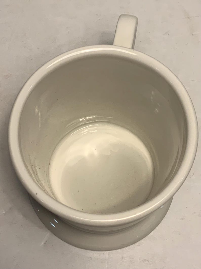 Puede incluir: Una taza de cer&aacute;mica blanca con asa. La taza tiene una forma cil&iacute;ndrica ancha con un borde ligeramente ensanchado y una base de pedestal. El interior y el exterior son de color blanco mate s&oacute;lido.