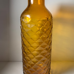 May include: A tall amber glass vase with a geometric diamond pattern.