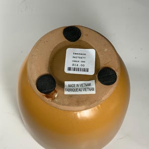 Pu&ograve; includere: Un'urna in ceramica gialla con un'etichetta in bianco e nero che recita "terrain 34275677 CHALK URN 14,00 &euro;" e "MADE IN VIETNAM FABRIQUE AU VIETNAM".