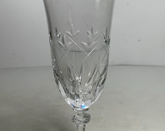 May include: A clear glass champagne flute with a cut crystal design. The flute has a tall, slender stem and a wide, round bowl.