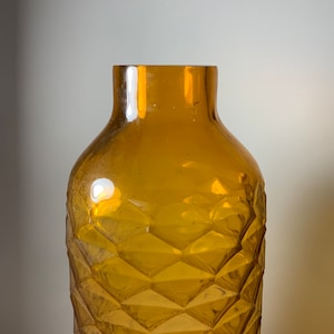 May include: An amber glass vase with a diamond pattern. The vase is empty and has a wide mouth.