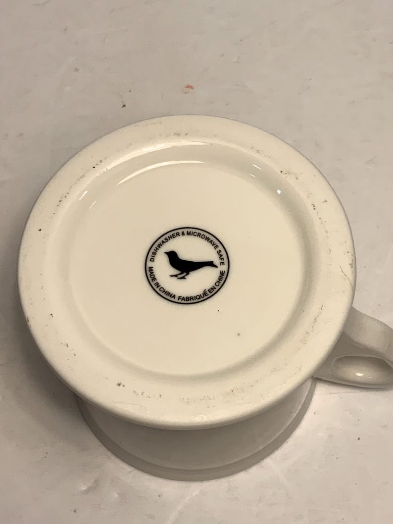 Puede incluir: Una taza de cer&aacute;mica blanca con asa negra y el texto "But First, Coffee" en estilo manuscrito. La taza est&aacute; sobre una superficie blanca. Ideal para bebidas calientes.