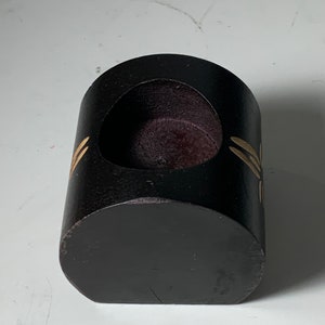 Puede incluir: Un portavelas de madera negro con una abertura redonda y un dise&ntilde;o de lib&eacute;lula dorada.