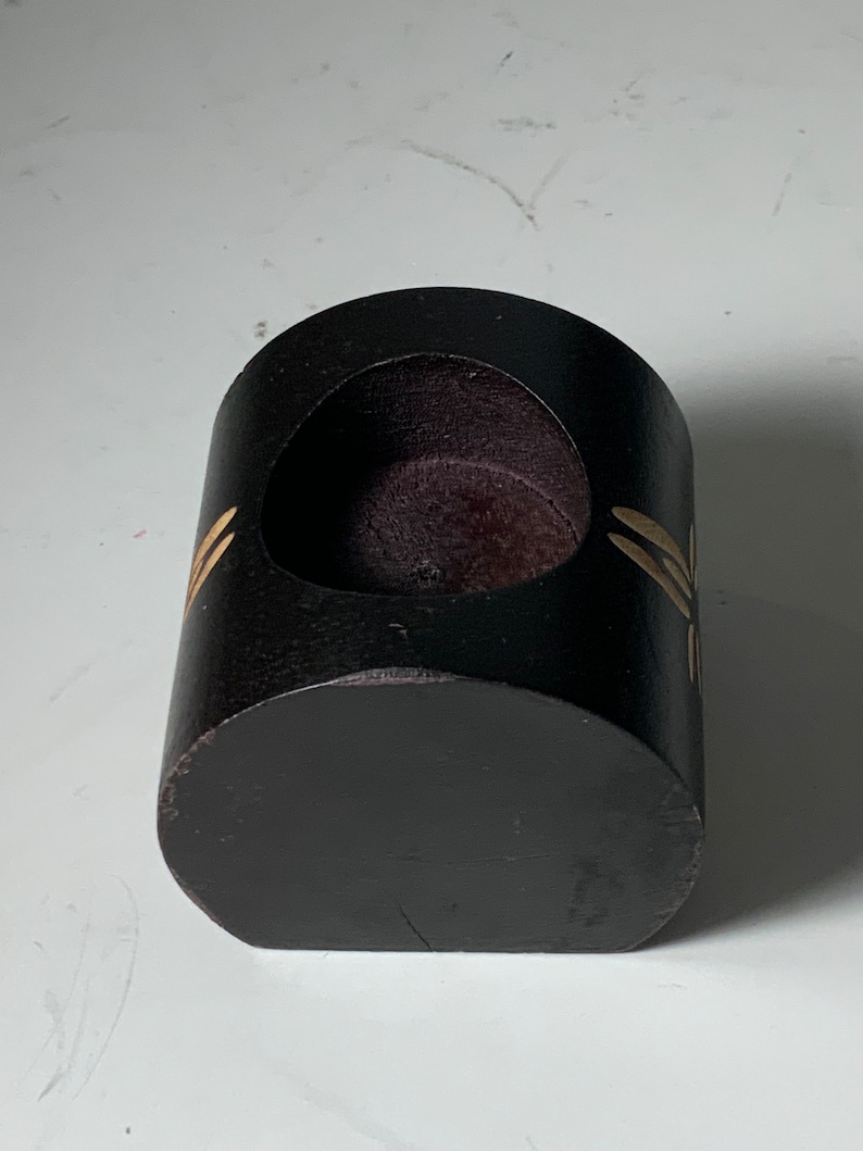 Puede incluir: Un portavelas de madera negro con una abertura redonda y un dise&ntilde;o de lib&eacute;lula dorada.