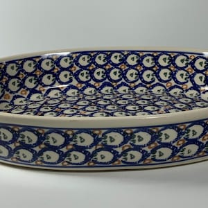 May include: Oval ceramic baking dish with a blue and white floral pattern. The dish has a cream-colored rim and a repeating design of blue and white flowers. A decorative serving piece for the kitchen.
